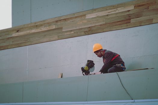 Construction worker with hard hat operating a circular saw on a building site.