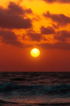 Dramatic sunset over the ocean at Akumal Beach, Mexico, with vivid orange and yellow hues.