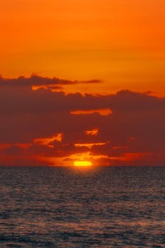 Stunning sunset over the ocean in Akumal, Quintana Roo, México, casting vivid orange hues.