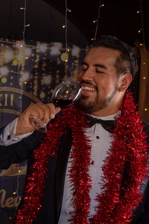 Free Man celebrates with red wine, dressed elegantly in Mexico City during a festive event. Stock Photo