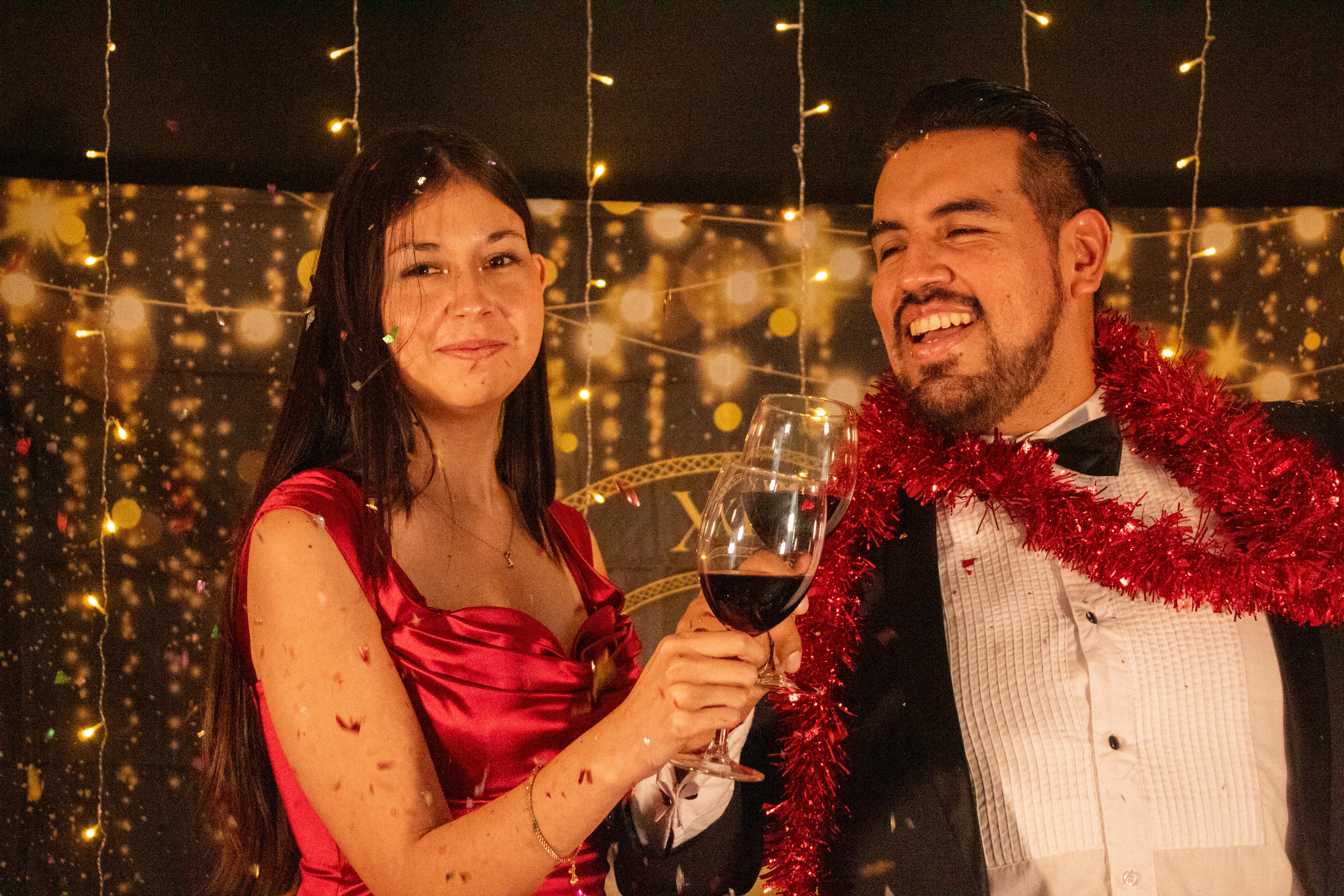 Smiling couple toasting with wine during a festive New Year's Eve party.