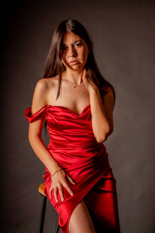 Free Portrait of a woman in a stylish red dress against a neutral background, exuding elegance and confidence. Stock Photo