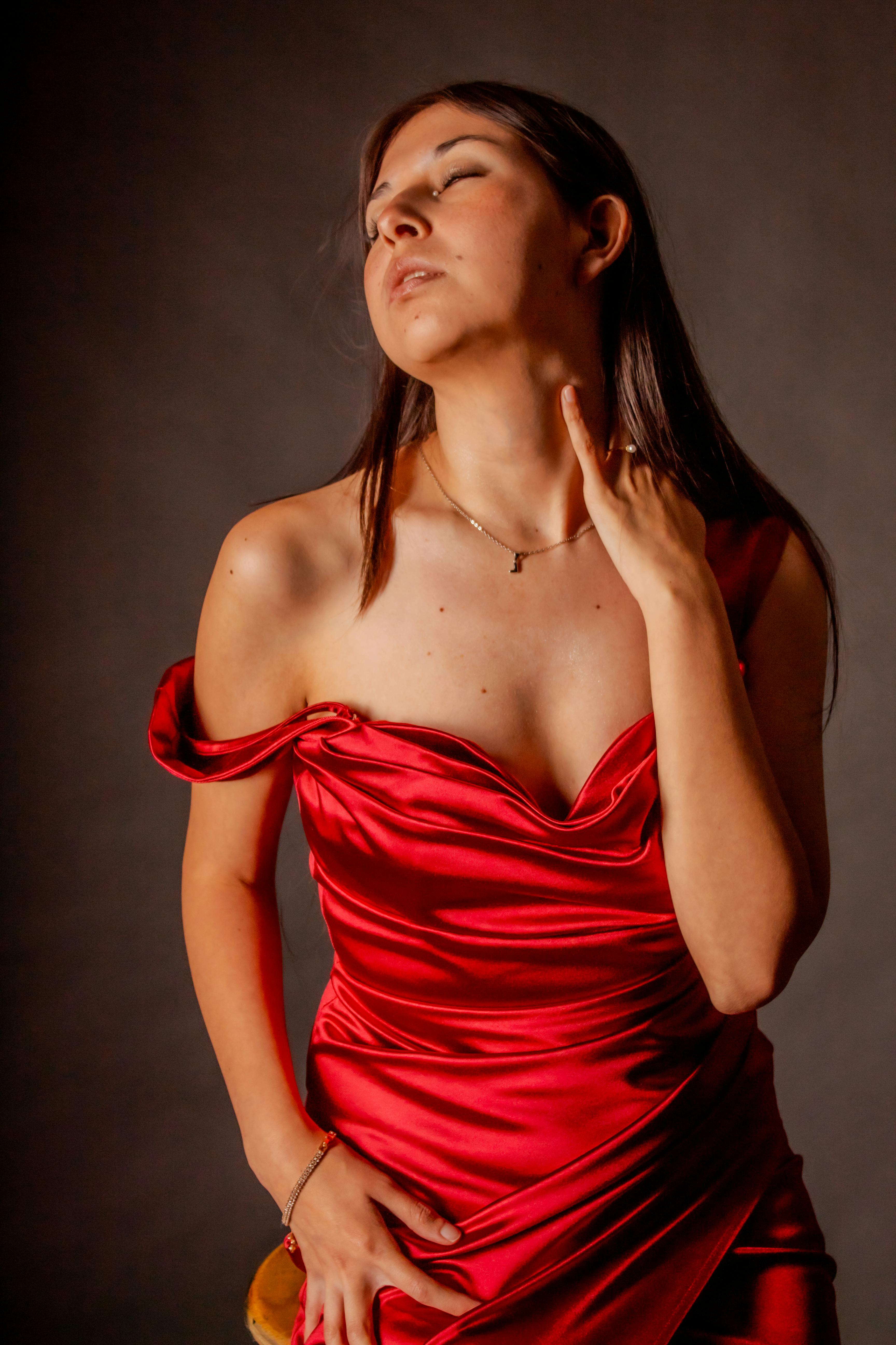 Kostenlos Künstlerisches Porträt einer eleganten Frau in einem roten Satinkleid, das Mode und Raffinesse ausstrahlt. Stock-Foto