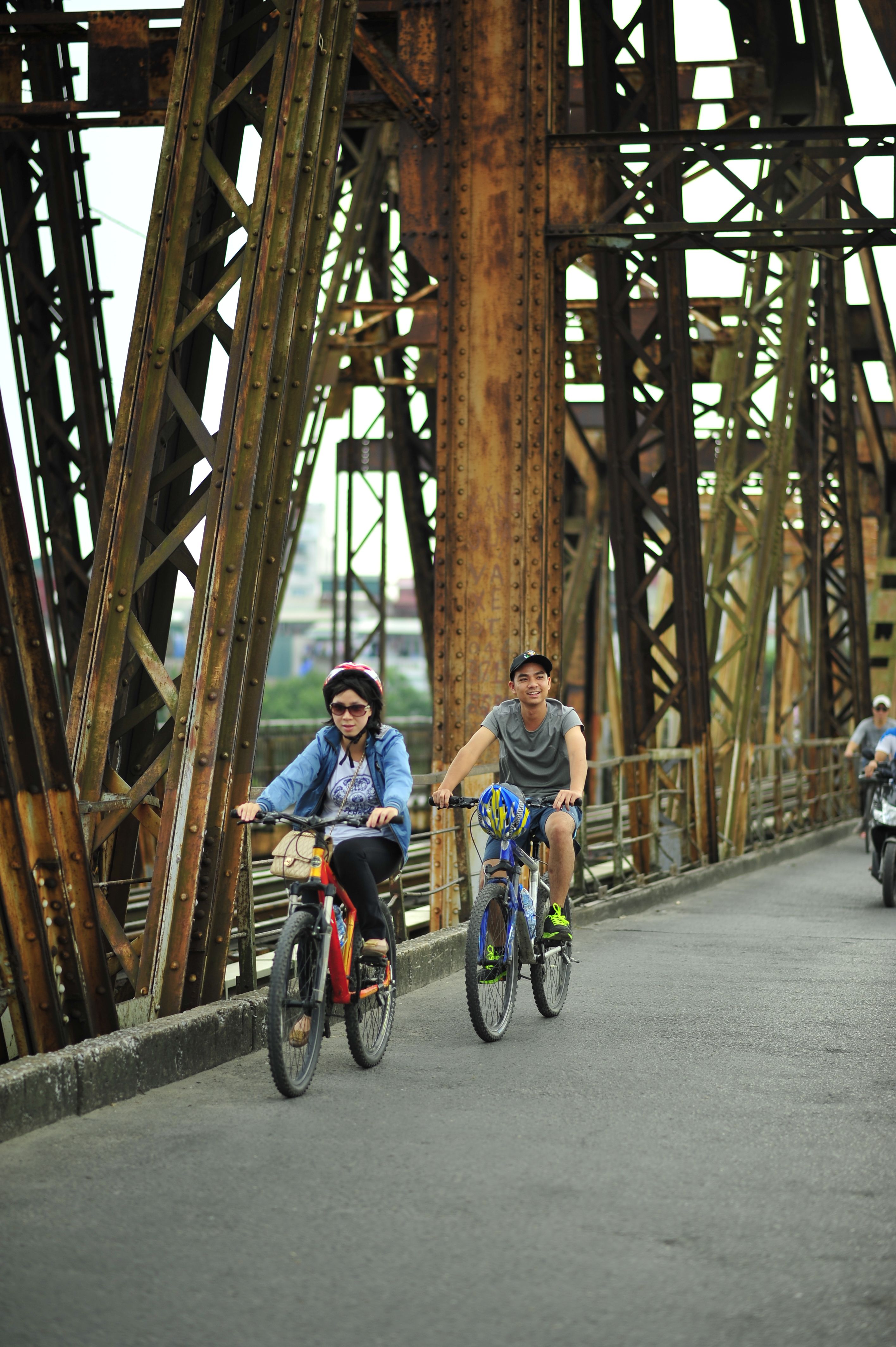 Urban cyclists riding across historic rusted bridge · Free Stock Photo