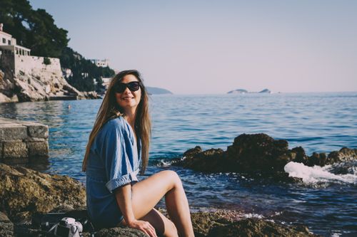 Free Young woman enjoying a sunny day by the Adriatic Sea in Dubrovnik, Croatia. Stock Photo