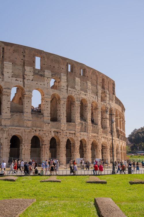 Free The Colosseum in Rome on a sunny day, bustling with tourists exploring its ancient architecture. Stock Photo