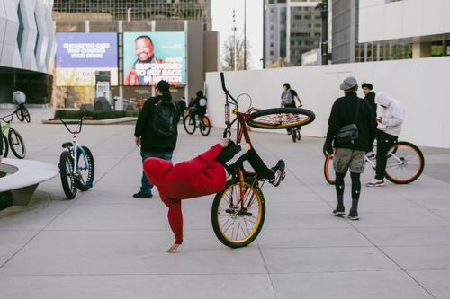 Free Young adults performing bike stunts and tricks in an urban environment showcasing street culture. Stock Photo