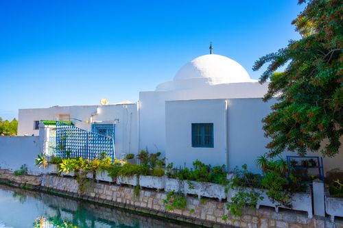 Free Beautiful dome-roofed building in Tunisia reflected on tranquil water under a clear blue sky. Stock Photo