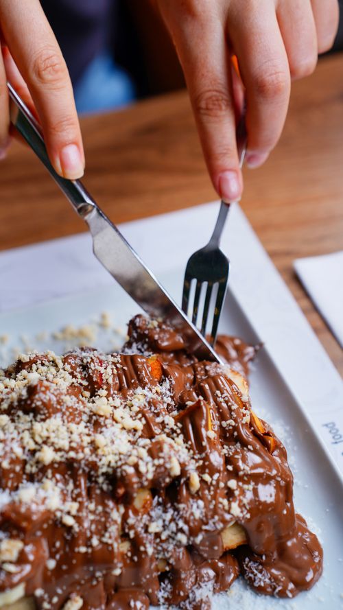 Free Close-up of a chocolate waffle being cut with fork and knife, highlighting a sweet dessert moment. Stock Photo