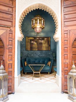 Beautiful Moroccan seating area with ornate arch, lantern, and sofa.