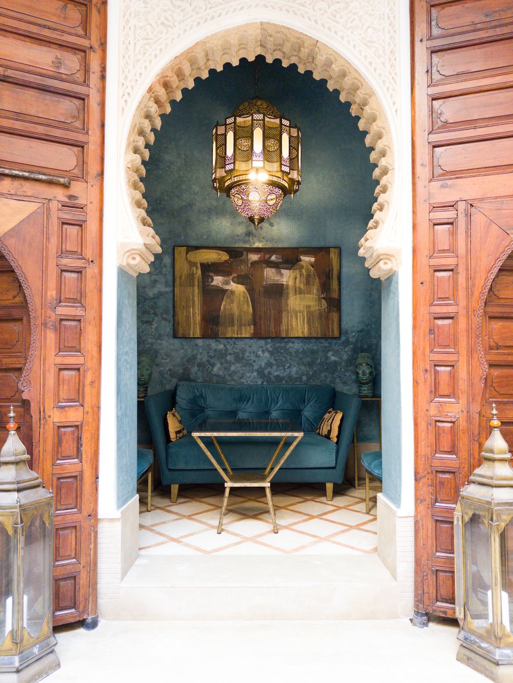 A salon behind carved cedar doors, with a velvet sofa under a brass lantern