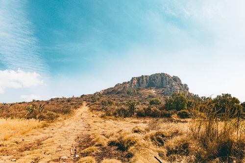 Free A picturesque rocky hill with dry grass under a clear blue sky, perfect for adventure travel. Stock Photo