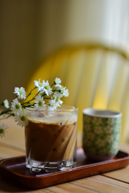 Free Elegant glass of iced coffee with delicate flowers on a wooden tray. Stock Photo