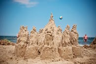 沙滩上，游客与海洋背景映衬着精美的沙堡，构成完美的夏日景象