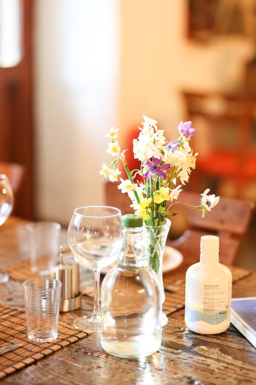 Free A rustic dining table featuring a vase of vibrant wildflowers and elegant glassware. Stock Photo