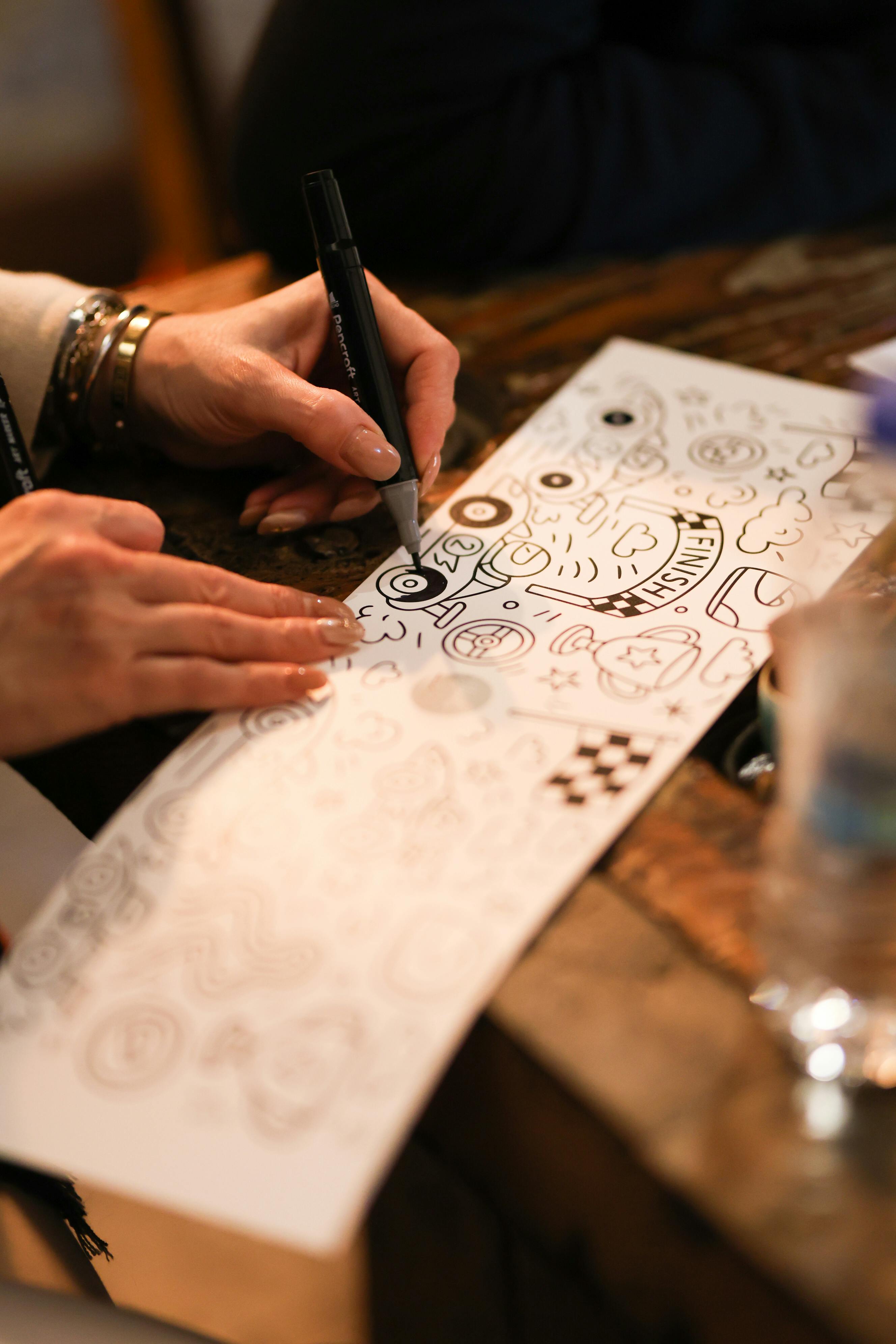 Gratis Nærbilde av hender som tegner på papir i et kunstnerisk verkstedmiljø, med vekt på kreativitet. Arkivbilde