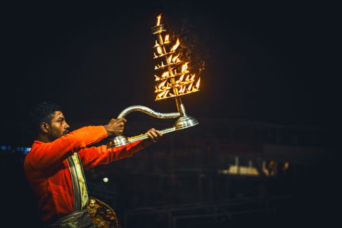 Free A man performs a Hindu ritual with a lit Aarti lamp during a night ceremony at Varanasi Ghats. Stock Photo