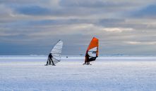 Two people ice sailing on a frozen sea in Helsinki, capturing a unique winter sport under a clear sky.