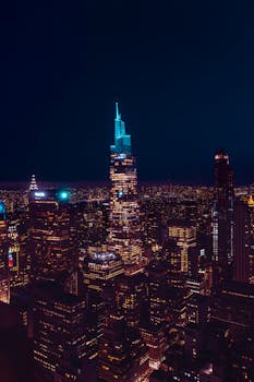 Stunning aerial view of New York City skyline at night with glowing skyscrapers and city lights.