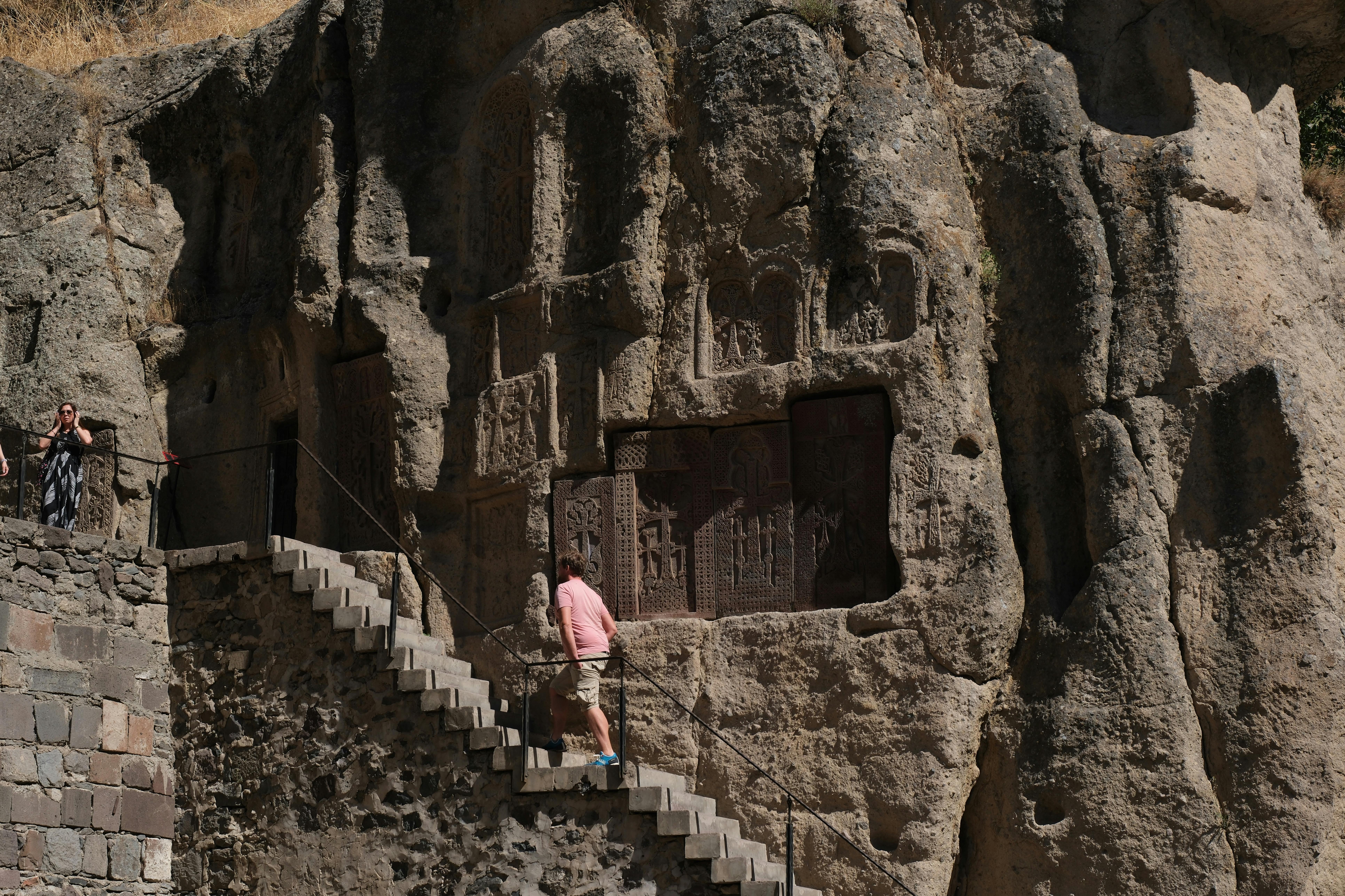Visitors exploring the ancient rock-hewn carvings at Geghard Monastery Armenia.