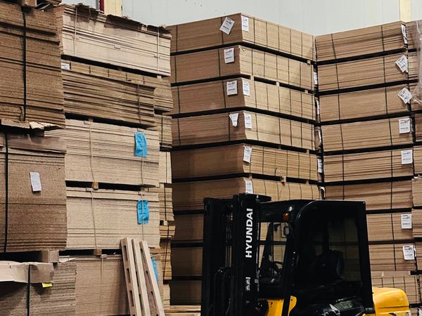 Grúa horquilla apilando cajas de cartón en una bodega espaciosa