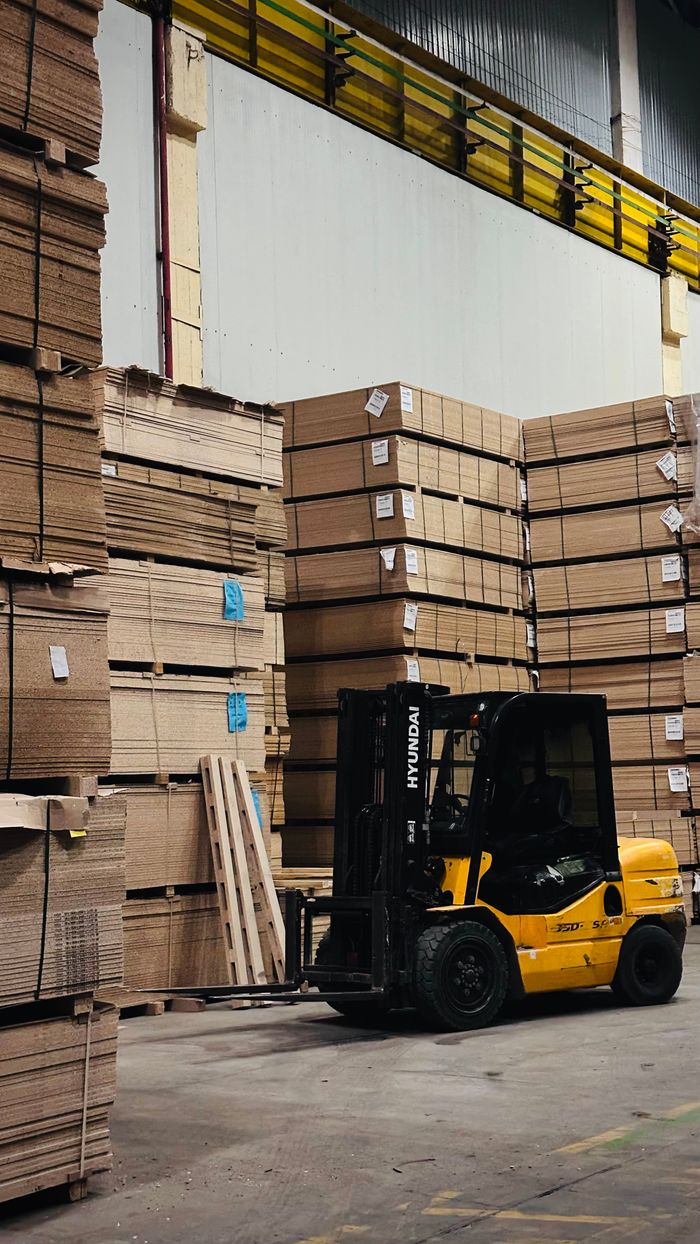 Forklift stacking cardboard in industrial warehouse