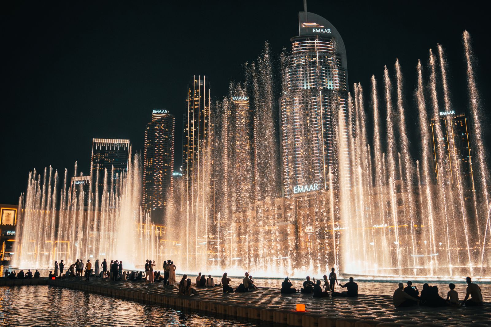 Dubai Fountain show lit up at night in front of the Downtown Dubai towers