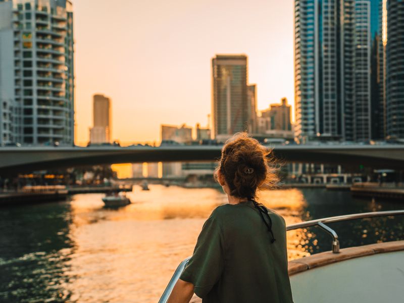 Guest on a yacht deck looking out over Dubai Marina at sunset