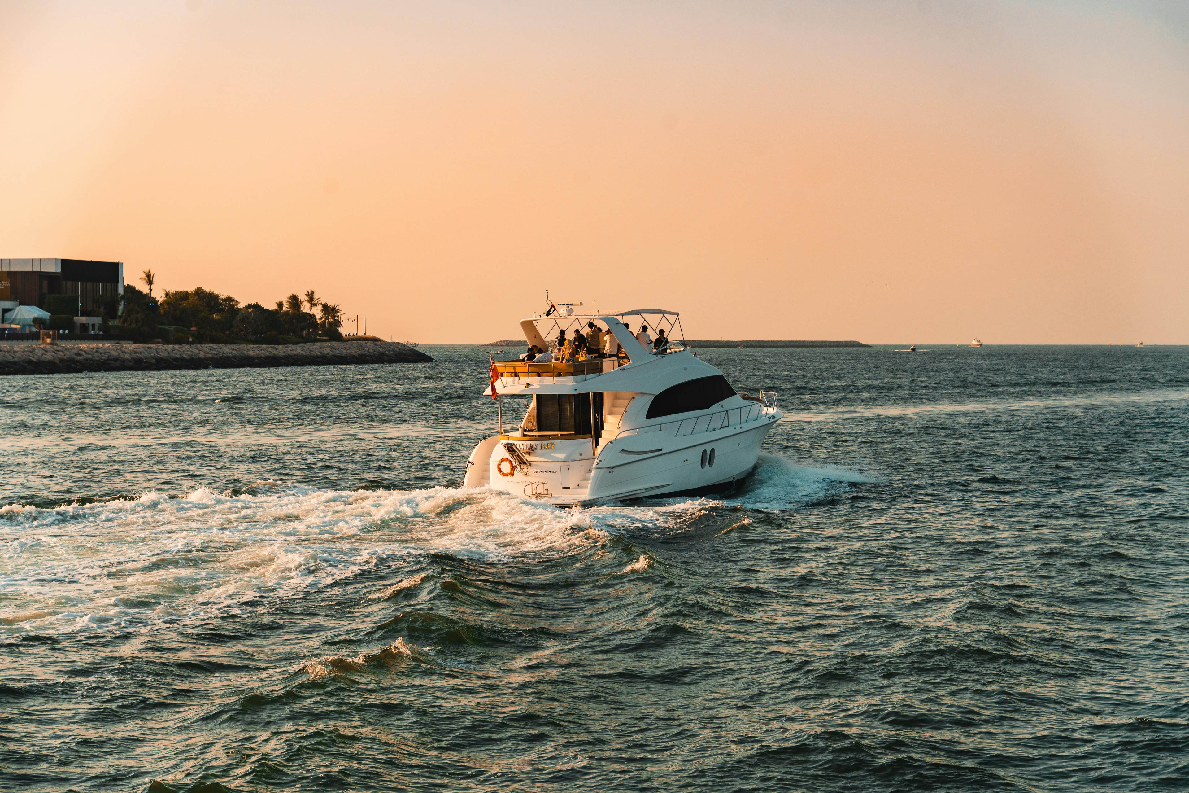 A luxury yacht cruises through the waters of Dubai at sunset, offering a serene and elegant escape.