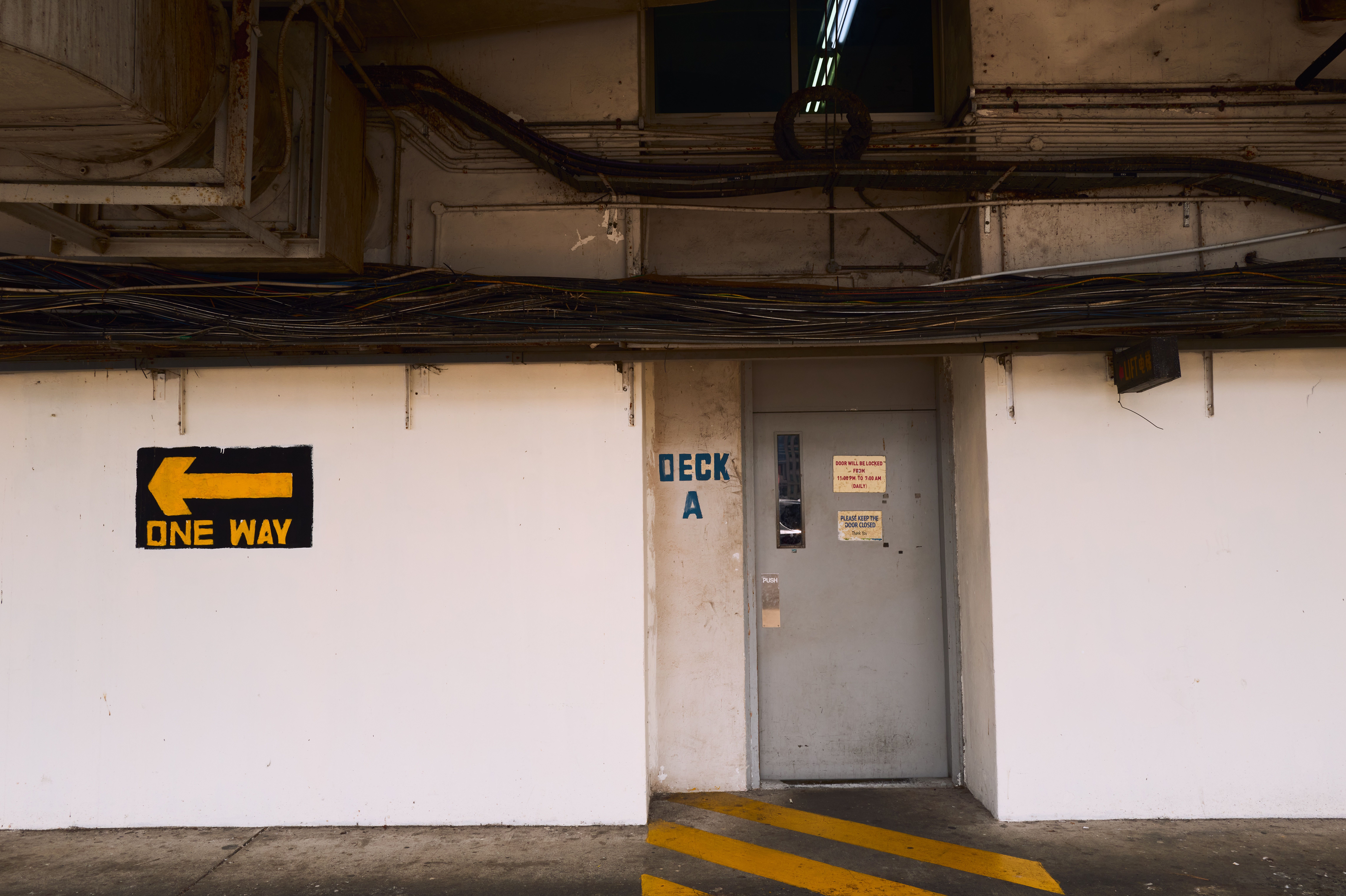 Exterior view of an industrial building with cables and a one way sign for navigation.
