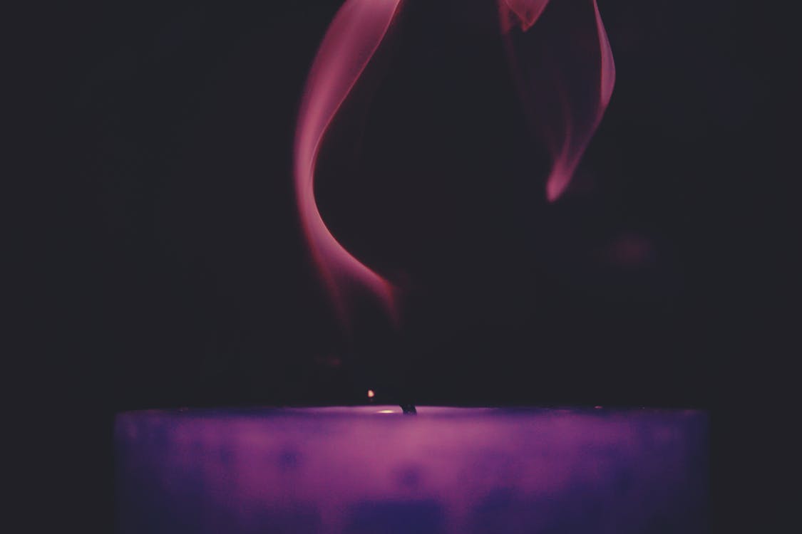 Lighted Purple Candle Against Black Background