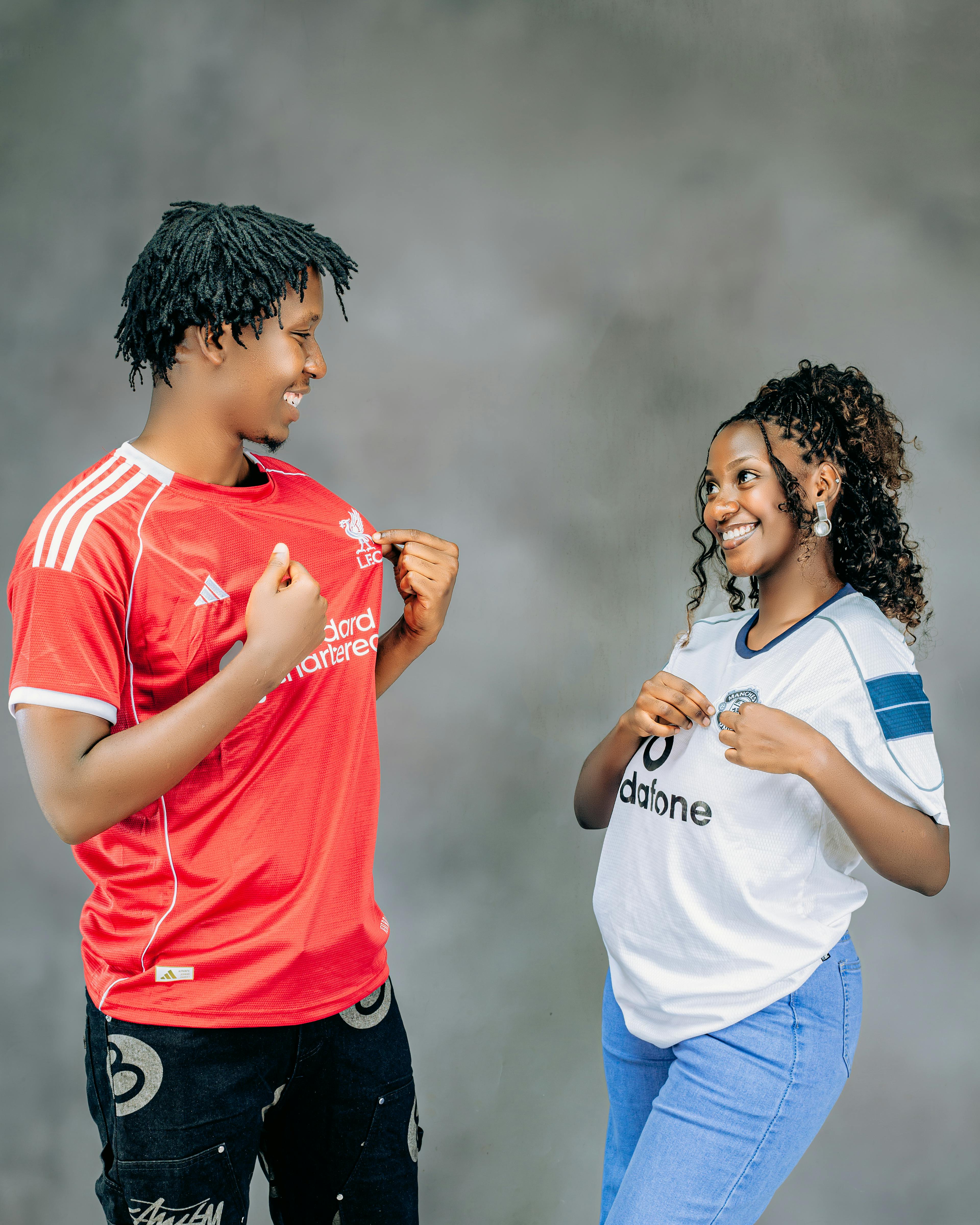 Zadarmo Dvaja usmievaví mladí dospelí predvádzajú športové dresy a vyjadrujú tímového ducha. Fotka z fotobanky