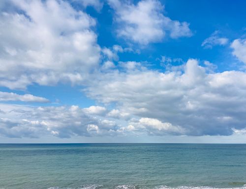 Free Serene ocean view with a vast blue sky filled with clouds, perfect for relaxation themes. Stock Photo