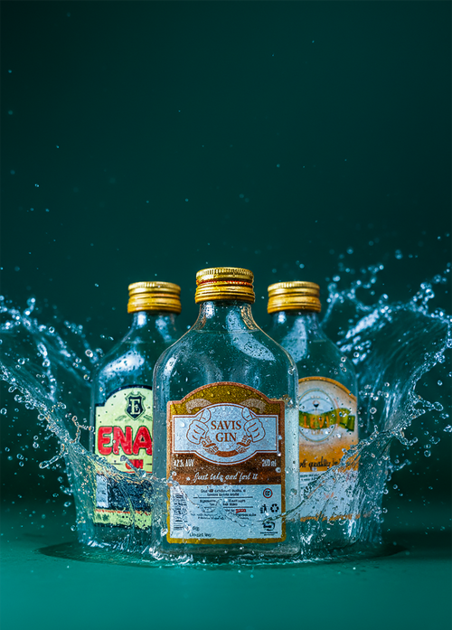 Free Three craft gin bottles splash into water on a teal background. Stock Photo
