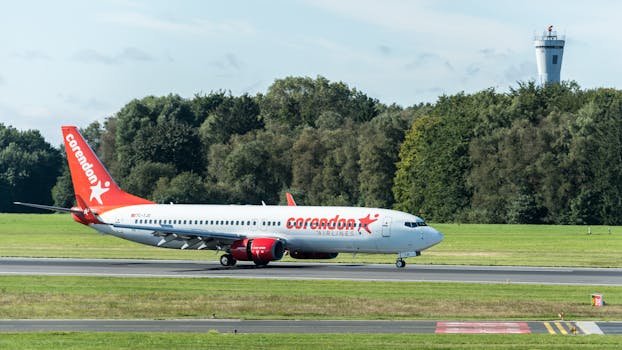 Corendon Airlines aircraft taxiing on the runway at Hamburg Airport on a sunny day.