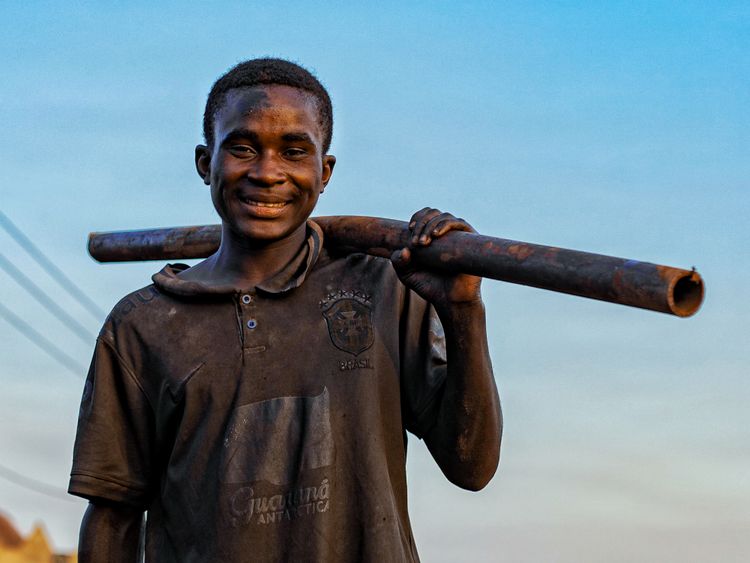 Smiling worker holding a metal pipe outdoors