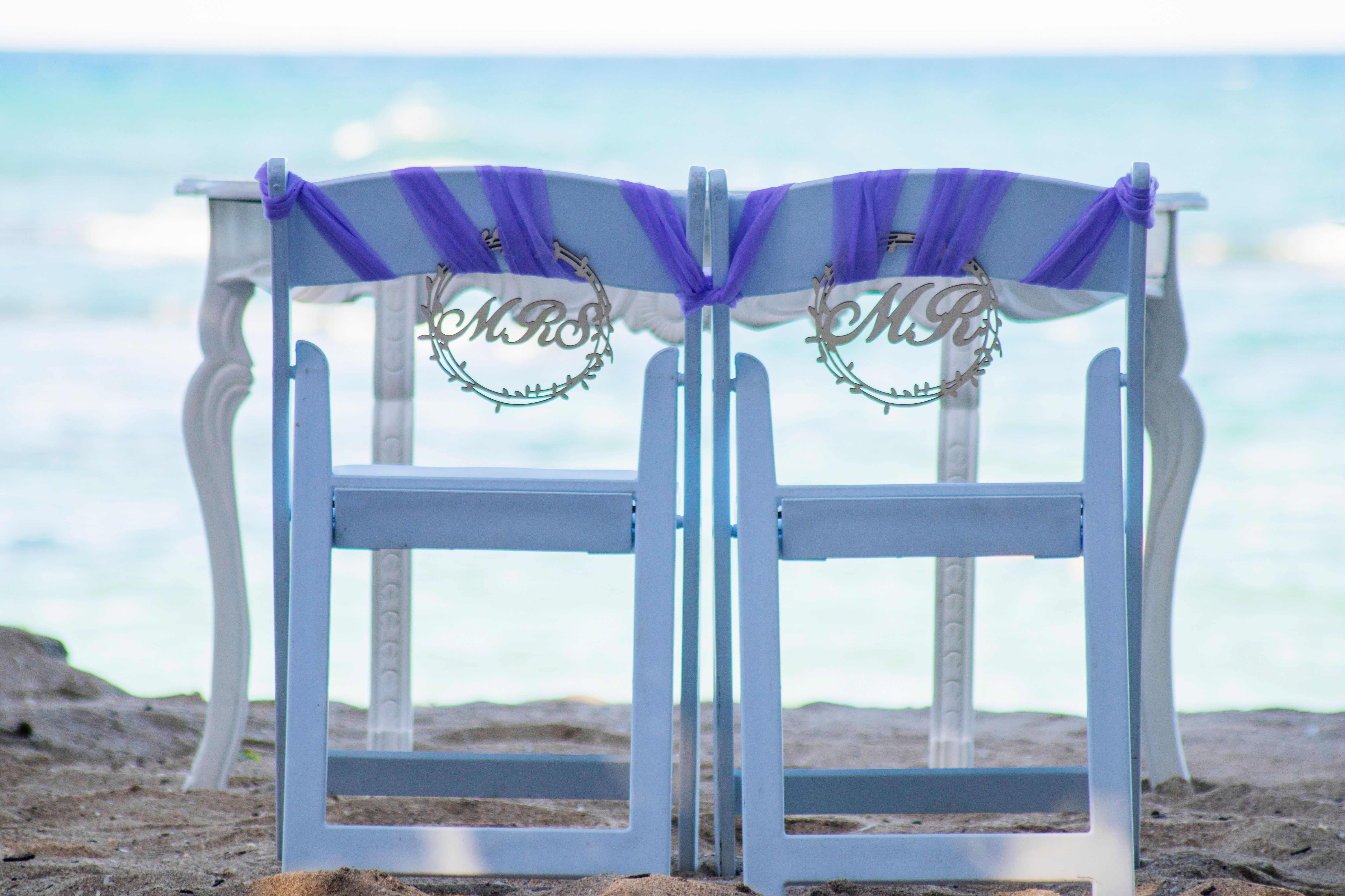 Charming beach wedding setup with elegant white chairs and purple decor on Puerto Plata beach.