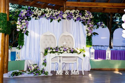 Free Beautifully decorated outdoor wedding venue with floral arches and chairs. Stock Photo