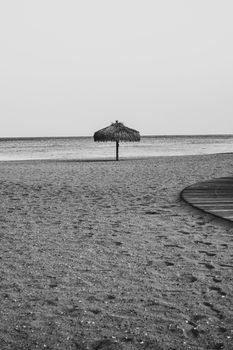 A solitary beach umbrella on a sandy shore in serene black and white.