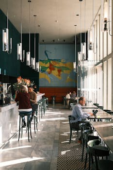 Elegant cafe interior with people working and socializing in natural light.