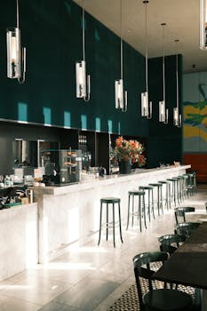 Elegant modern cafe interior featuring bar stools, hanging lights, and sunlit ambiance.