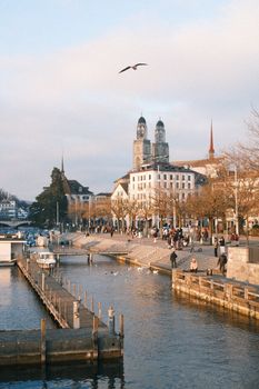 Scenic view of Zurich skyline with Grossmünster and river in warm afternoon light.