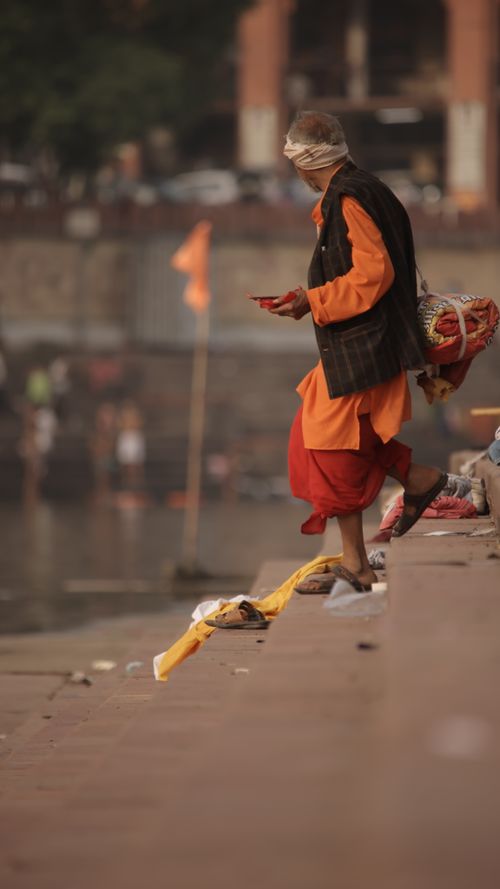 Free A monk in traditional attire walks along a riverbank with offerings. Stock Photo