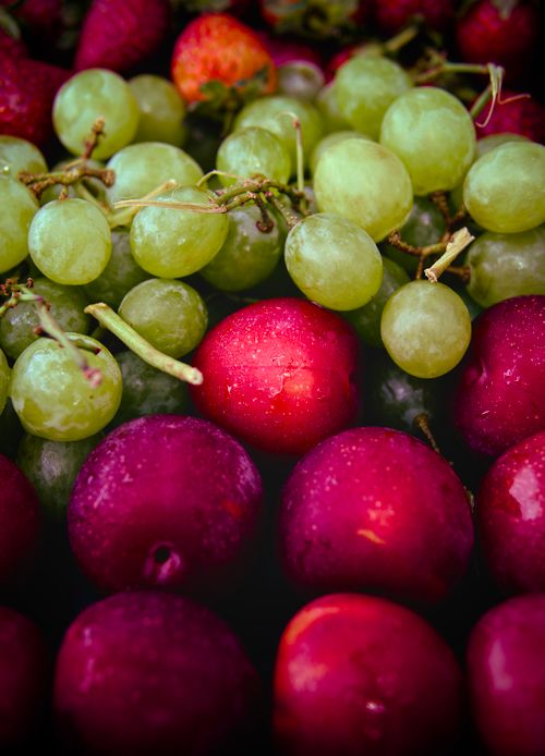 Free A vibrant close-up of red plums and green grapes with water droplets, showcasing fresh fruit textures. Stock Photo