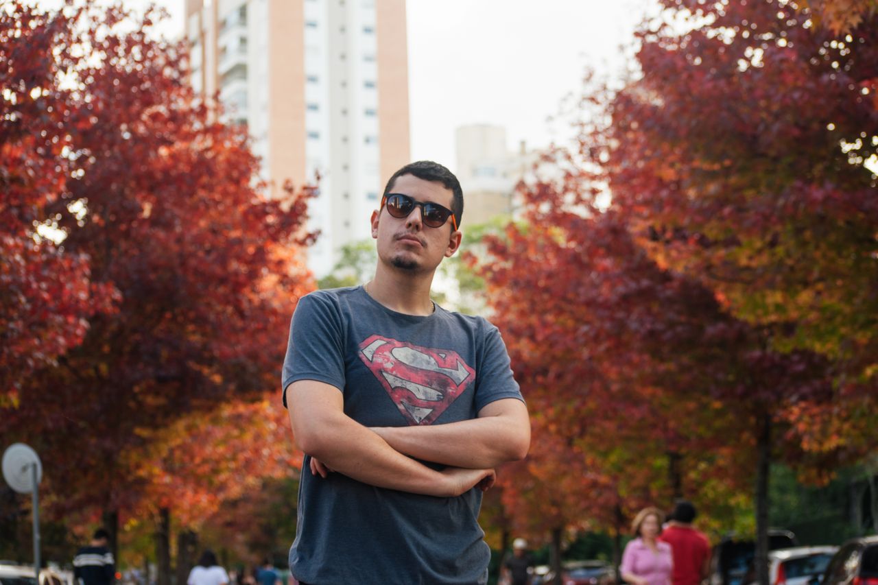 stylish man wearing sunglasses standing confidently amidst vibrant aut