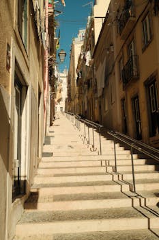 Sun-drenched stairs lead through a picturesque street in Lisbon, Portugal.