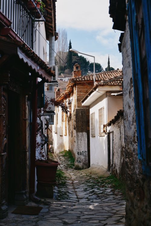 Free Narrow alley in a historic European village with cobblestone path and charming houses. Stock Photo