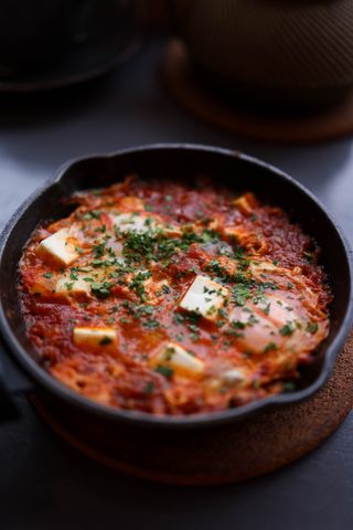 Shakshuka cooking in a cast-iron skillet, photo by Valeria Boltneva on Pexels