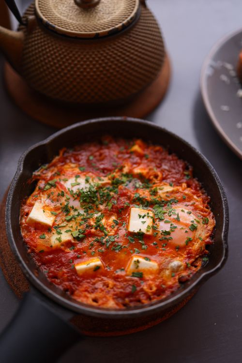 Free Tasty shakshuka with eggs, tomatoes, and herbs in a cast iron skillet. Stock Photo