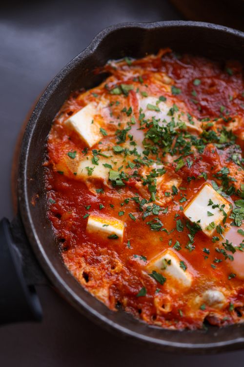 Free Hot and savory shakshuka with poached eggs and feta cheese in a rustic skillet. Stock Photo